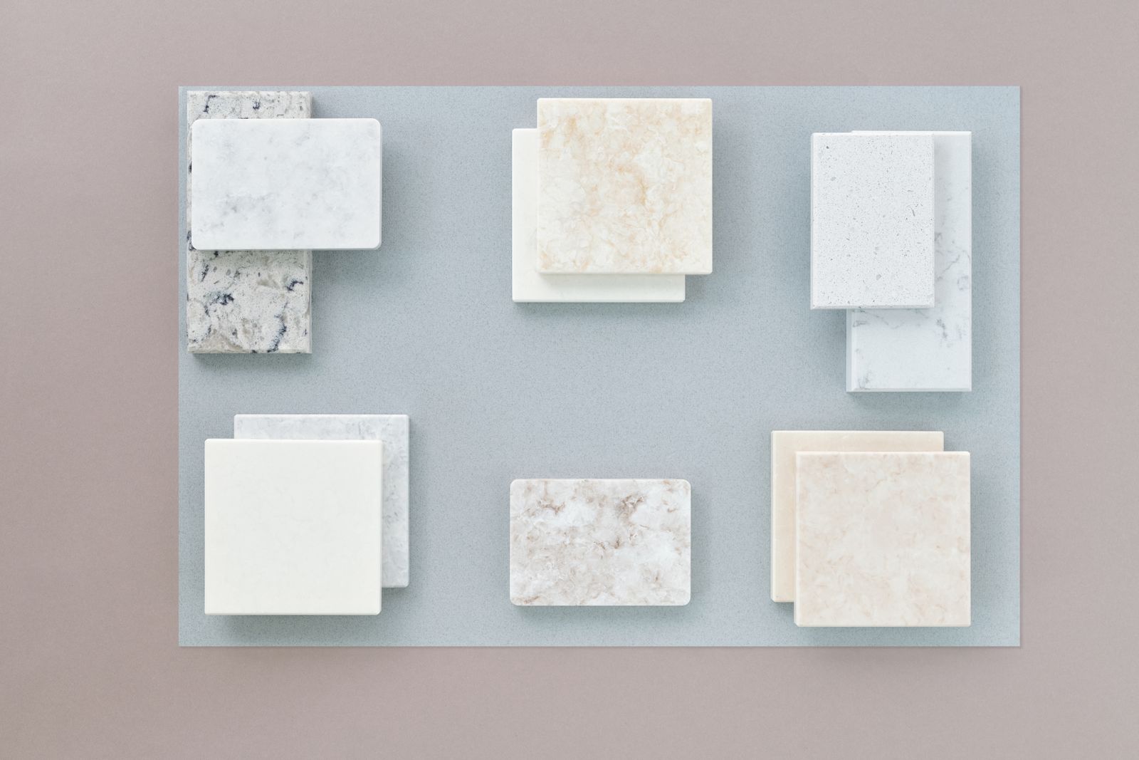 Flat lay image of various marble tile samples arranged on a neutral surface, perfect for design projects.