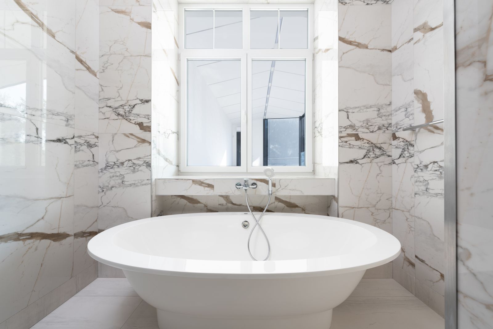 A freestanding bathtub in a bright tiled bathroom